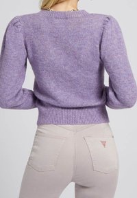 Lichtpaarse, gestructureerde gebreide trui met pofmouwen en een geribbelde zoom. Gecombineerd met licht beige broek met achterzakken en logo detail.