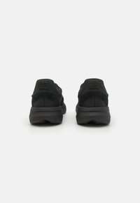 Black sneaker features a textured mesh upper with suede accents, a cushioned sole, and a rounded heel for comfort and support.