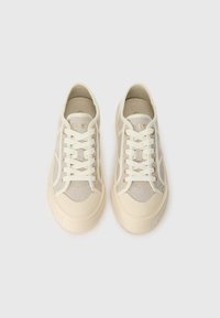 Sapatilhas beges com um design em rede, atacadores de cor clara e solado em borracha. Apresenta uma marcação discreta de um lado.