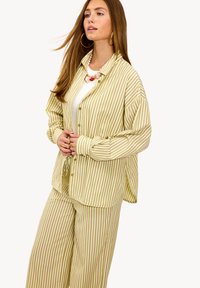 Conjunto de loungewear a rayas en verde claro y beige. Tejido suave con una camiseta de corte relajado y pantalones de pierna ancha con rayas verticales.