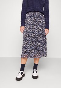 Floral pleated midi skirt in navy, purple, and white. Lightweight material, elastic waistband, with a flowy design. Worn with white shoes.