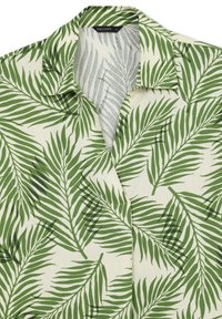Short-sleeve shirt featuring a green palm leaf pattern on a cream background, with a collar and a relaxed fit design.
