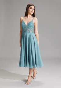 Ein türkisfarbendes Chiffonkleid mit tiefem V-Ausschnitt und besticktem Oberteil, verstellbaren Trägern und fließendem A-Linien-Schnitt.