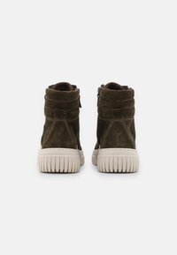 Green suede ankle boots with a rounded toe, ribbed white rubber sole, and side zippers for easier wear.