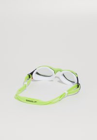 Speedo zwembril met groene siliconen rand, witte oogkappen, verstelbare band en getinte lenzen. Geschikt voor competitief zwemmen.