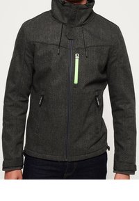 Veste texturée gris foncé avec col montant et fermeture éclair. Présente un accent de fermeture éclair vert et des poches latérales. Conçue pour la chaleur.