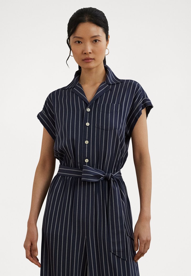 Marineblauw gestreepte shirtjurk met korte mouwen, knopen aan de voorkant en borstzak. Inclusief een gestrikt tailleband en lichtgewicht stof.