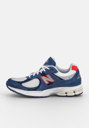 Blue and white New Balance 2002R sneaker with red accents, white laces, mesh and suede materials, and cushioned sole.