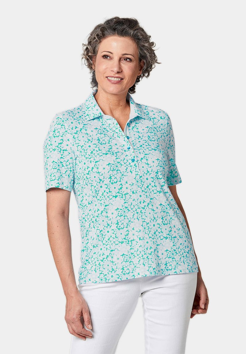 Lichtblauwe polo met korte mouwen met een bloemenpatroon in teal en wit, met een kraag en knopenlijst, gemaakt van zacht materiaal.