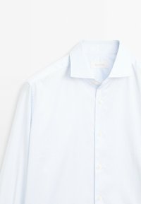 Camicia a righe blu chiaro realizzata in un tessuto dalla texture liscia, con colletto classico e bottoni bianchi lungo la patta.