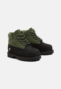 Stivali in pelle nera e verde con design lacciato, collo imbottito e suola in gomma spessa con profondi battistrada per una migliore aderenza.