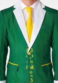 Giacca verde con collo in pelliccia sintetica bianca, dettagli gialli e ricami gialli decorativi. Presenta una chiusura a bottone e tasche laterali.
