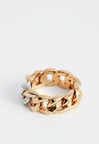 Anello a catena alla moda in oro lucidato con un piccolo dettaglio in argento, mostrato su uno sfondo bianco semplice.