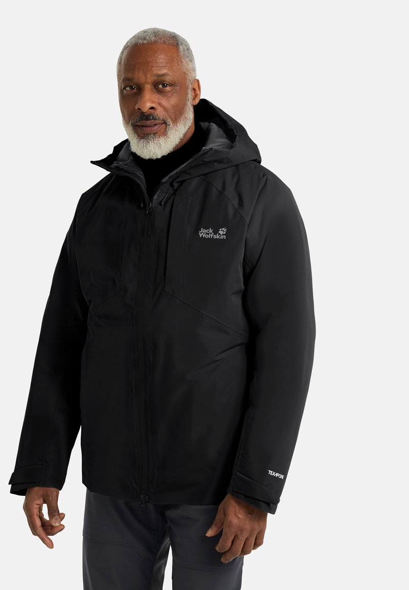 Giacca impermeabile nera di Jack Wolfskin con zip frontale, cappuccio e tessuto testurizzato; presenta dettagli con logo sul petto e sulla manica.