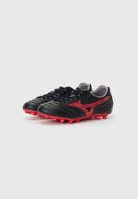 Botas de fútbol de cuero negro con acentos rojos, que cuentan con un diseño texturizado, seis tacos rosas y un cuello acolchado gris para mayor comodidad.