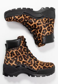 Ankle boots s leopardím potiskem a černými koženými akcenty, silnými gumovými podrážkami a kovovými očky. Mají strukturovaný povrch připomínající kožešinu.