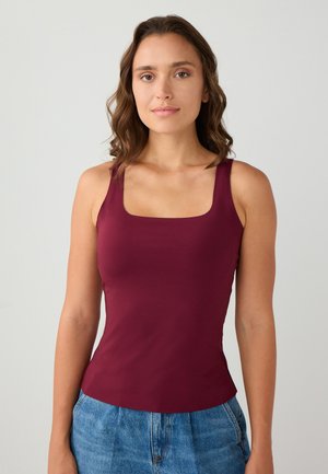 Bordeaux tanktop gemaakt van gladde, rekbare stof. Heeft een vierkante halslijn en brede schouderbanden, gecombineerd met high-waisted denim shorts.