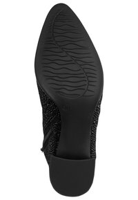 Zwarte enkellaars met een gestructureerde bovenzijde, slank ontwerp, puntige neus en een gedetailleerd loopvlakpatroon op de rubberen zool. Ritsaccentdetail.