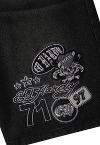 Tissu en denim noir avec des logos Ed Hardy brodés en blanc, un crâne avec un cœur et une bannière, des étoiles, ainsi que les chiffres 71 et 97.