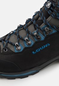 Stivaletto da escursionismo nero con accenti blu, realizzato in materiali scamosciati e sintetici, occhielli rinforzati e lacci decorati per una chiusura sicura.