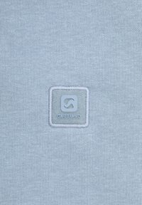 Lichtblauwe gebreide stof met een vierkante stoffen patch met reliëflogo met de tekst "GarbianoQ." Gladde textuur met subtiele stikdetails.