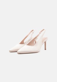 Escarpins slingback en satin beige doux avec un bout pointu, ornés d'une bordure perlée le long du bord et d'un talon fin et transparent.