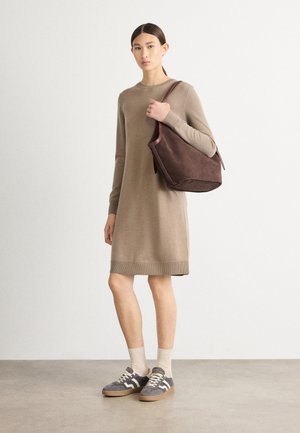 Beige gestricktes Kleid mit langen Ärmeln und geripptem Saum, kombiniert mit einer braunen Wildleder-Umhängetasche und grauen Turnschuhen mit weißen Schnürsenkeln.