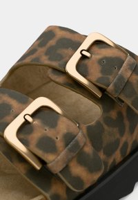 Sandales imprimé léopard avec deux boucles dorées, matière en daim doux et semelle intérieure moulée. Semelle plateforme noire et design ajouré.