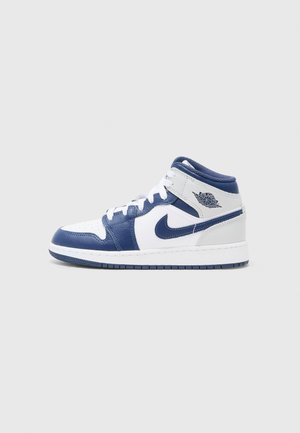Baskets montantes Nike Air Jordan en cuir blanc et bleu marine avec des lacets blancs et le logo Air Jordan sur la cheville.