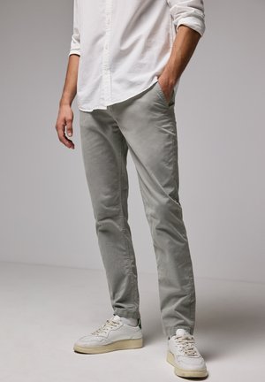 Grijze katoenen chinos met een slim fit, voorzien van zijzakken en een gladde textuur, gecombineerd met witte sneakers en een overhemden.