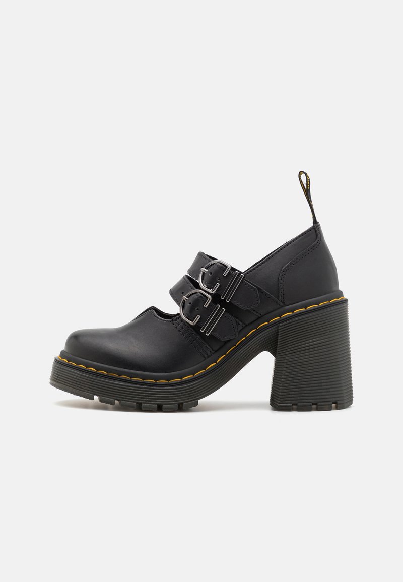 Sapatos de salto alto pretos com uma sola texturizada, apresentando duas fivelas prateadas, costura amarela e um laço na parte de trás para fácil colocação.