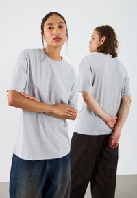Gray short-sleeve t-shirts made of soft material, featuring a round neckline and a relaxed fit, worn by models against a neutral background.