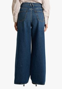 Jeans di jeans a gamba larga e vita alta in blu scuro, con finitura testurizzata, cinque tasche e coulisse regolabile in vita.