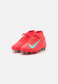 Bottes de football rouges avec une surface texturée, arborant un swoosh Nike turquoise, un design à haute cheville et des crampons turquoise pour l'adhérence.