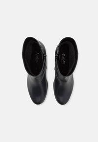 Botine negre din piele, cu o textură netedă, închidere cu fermoar pe lateral și interior căptușit pentru confort. Design minimalist.