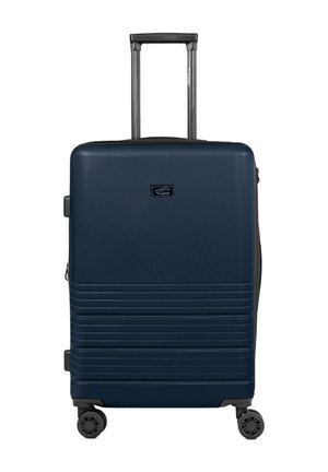Hard-shell suitcase in navy blue, featuring a textured finish, vertical ridges, two multi-directional wheels, and a retractable handle.