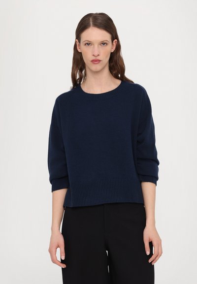 Navy blue knitted sweater with a crew neck, dropped shoulders, and ribbed hem. Fabric appears soft with a smooth texture.