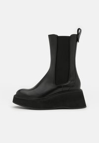 Stivaletto alla caviglia in pelle nera con pannelli laterali elastici, punta arrotondata e suola a zeppa spessa, caratterizzato da una texture liscia e da un'asola posteriore.