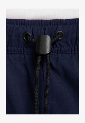 Ceinture élastique bleu marine avec cordon noir passant dans des œillets en métal noir, fixé par un verrouillage en plastique noir.