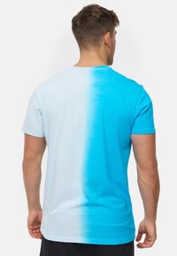 Camiseta de color azul claro con un degradado que se desvanece en azul brillante. Mangas cortas, escote redondo y textura de algodón suave.