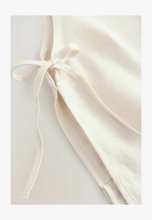 Leinenbekleidung in Off-White mit weicher Textur, ausgestattet mit einer seitlichen Bindung und sauberem Stich entlang der Kanten.