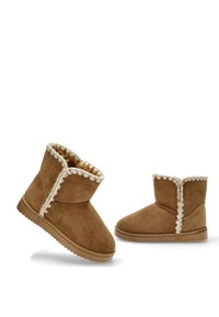 Botas de tobillo de ante marrón con forro de felpa, borde ondulado en la apertura y suela de goma plana. Anguladas para una vista óptima de los detalles.