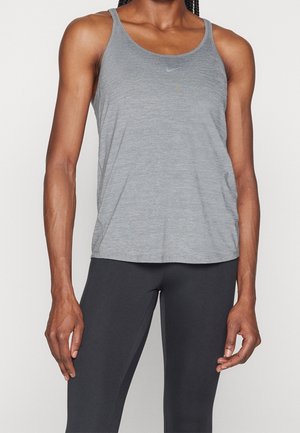 Person trägt ein graues ärmelloses Nike Tanktop und schwarze enganliegende Leggings, steht mit entspannten Armen seitlich am Körper.