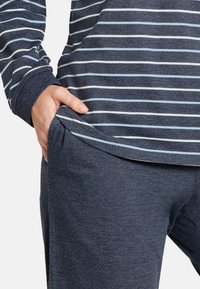 Navyblaues, langärmliges gestreiftes Oberteil mit hellblauen und weißen Streifen; kombiniert mit passenden navyblauen Hosen mit einer Seitentasche.