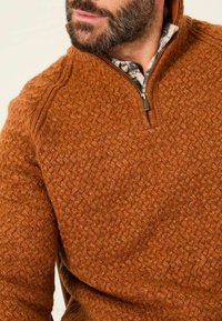 Brauner Strickpullover mit Reißverschlusskragen. Verfügt über einen strukturierten Stoff mit einem gewebten Muster und einem warmen, rustikalen Farbton.