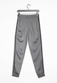 Grijze sportbroek met een gladde textuur, voorzien van zwarte zijstrepen en een elastische tailleband, tentoongesteld op een zwarte hanger.