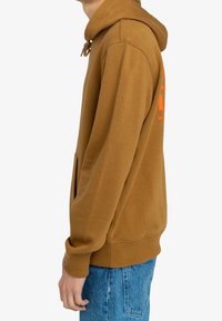 Brown hooded sweatshirt with front pocket, drawstring hood, and large graphic text in bright orange; soft fabric, relaxed fit, ribbed cuffs.
