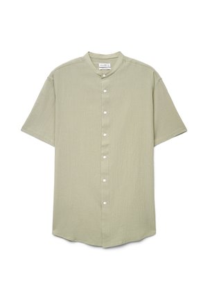Chemise à manches courtes de couleur vert clair avec col mandarin et boutons blancs, posée à plat sur un fond blanc.