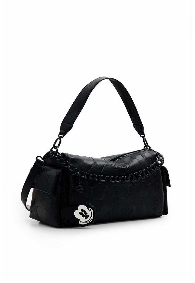Sac à bandoulière en cuir noir avec motifs embossés, détail chaîne et porte-clés en forme de tête de Mickey Mouse accroché sur le côté.
