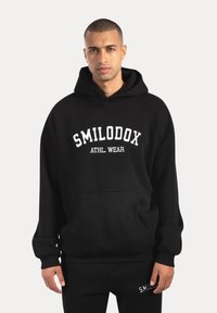 Czarna bluza z kapturem wykonana z miękkiego materiału, z przednią kieszenią, z białym napisem "SMILODOX ATHL. WEAR" na klatce piersiowej oraz ściągaczami przy rękawach.